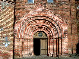 Südportal der Kirche (herausragend, unregelmäßig abgetreppt); jeweils an den Abtreppungen sind zwei Säulen vorgelagert, die teilweise Schildkapitelle aufweisen